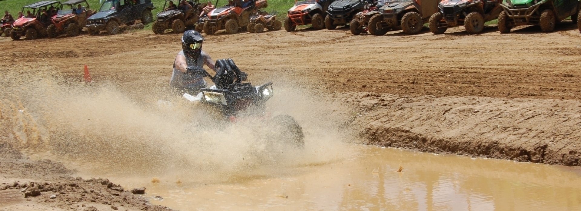 man riding four wheeler through mud puddle
